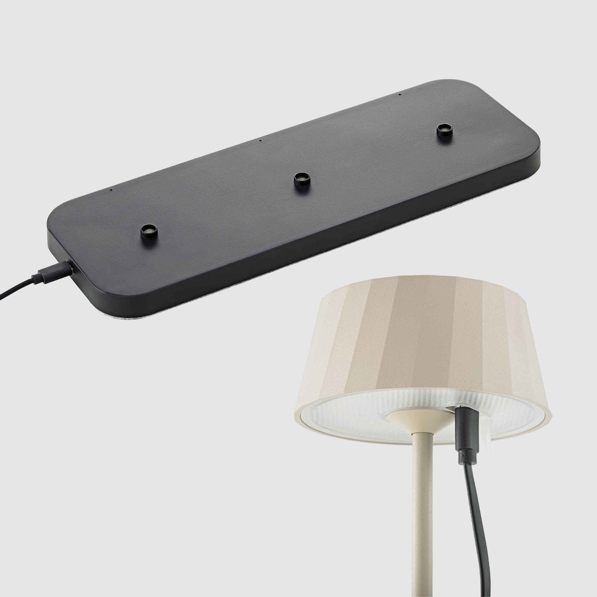 Dreifach-Ladestation und Sigor Facetta Remote Akku-Tischleuchte in Dünenbeige mit eingestecktem USB-C-Kabel.