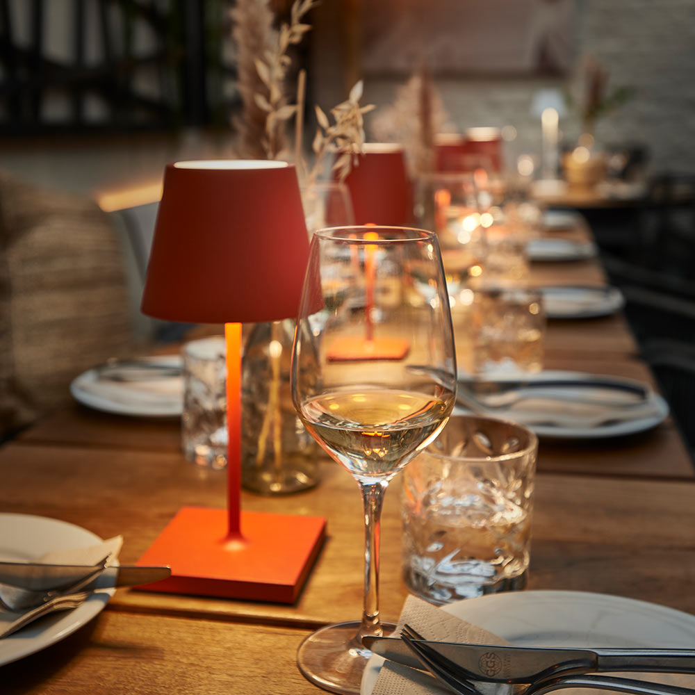 Die Akku-Tischleuchte Sigor Nuindie 3.0 mini in rot auf einem gedecktem Tisch im Restaurant