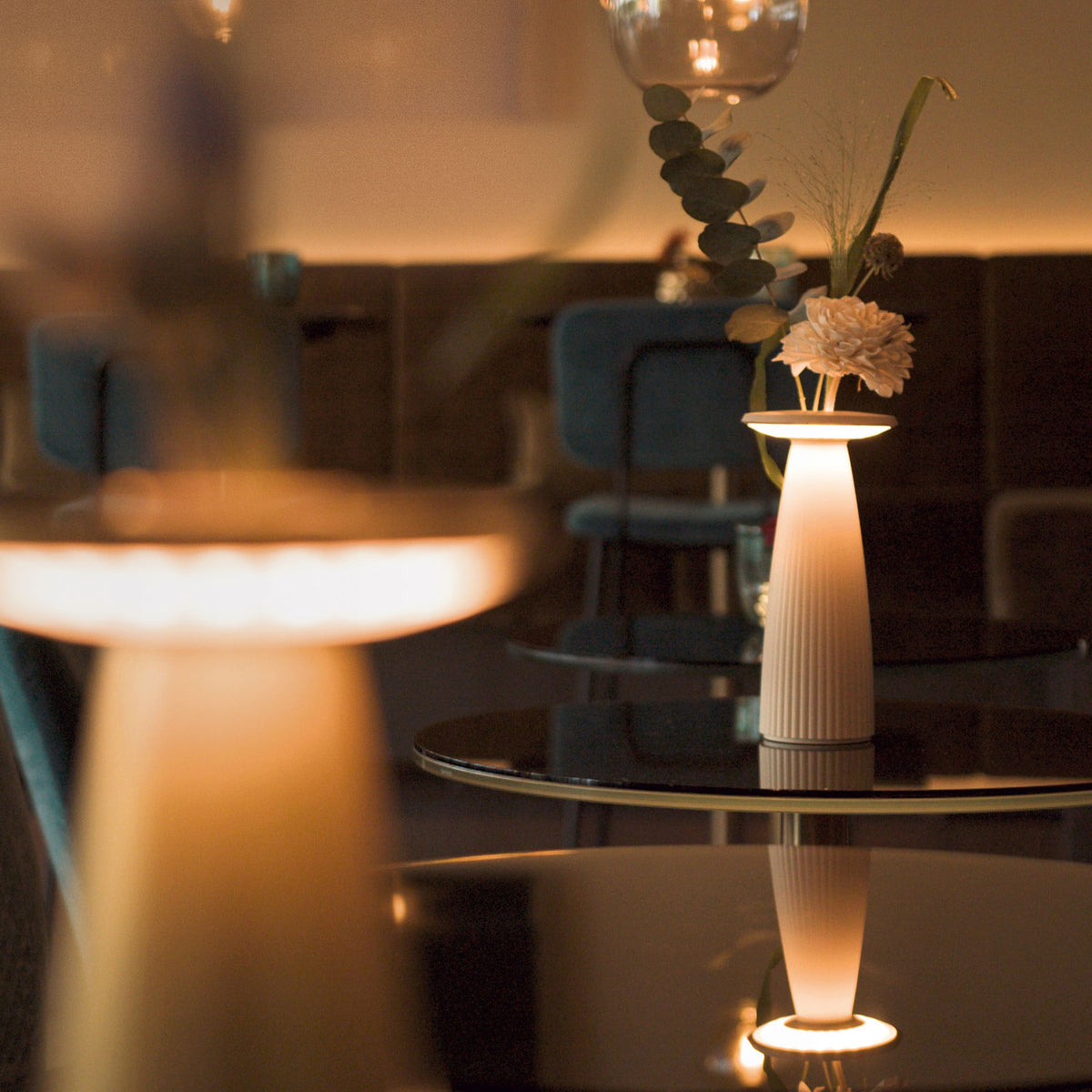 Sigor Nuflair Akku-Tischleuchte als Vase mit LED-Beleuchtung und Blumen auf einem Restauranttisch
